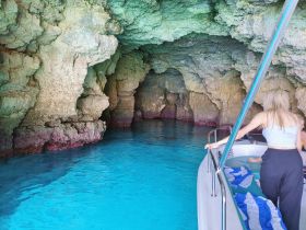 A scenic view of a boat exploring a stunning cave with crystal-clear waters, showcasing the beauty of nature and adventure on the water.