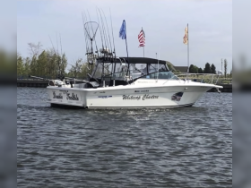 A sleek fishing boat named 'Double Trouble' is seen cruising in calm waters, showcasing its fishing gear and flags, ideal for charter adventures.