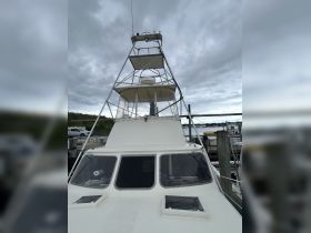 A detailed view of the front exterior of a boat docked at the marina, showcasing its structure and design against a cloudy sky.