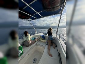 Two friends enjoy a relaxing moment on the boat, capturing the scenic views as they cruise along the water — perfect for memorable outings and adventures.