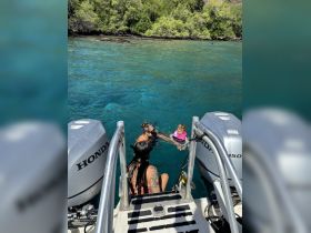 A family enjoys a fun day in the water, with a child in a pink life jacket swimming alongside an adult. Perfect for memorable water activities and family bonding.