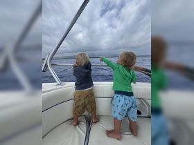 Two children enjoy a boat ride, pointing out to the ocean as they explore the beautiful seascape — a perfect moment of adventure on the water.