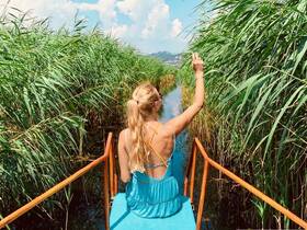 A woman enjoys a scenic boat ride through lush greenery, capturing the beauty of nature while exploring tranquil waterways.