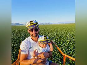 A joyful moment captured with a father and child wearing captain hats, enjoying a sunny day outdoors — perfect for family adventures and creating lasting memories.