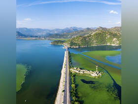 A stunning aerial view of a scenic landscape featuring a winding road and lush green waters, showcasing the natural beauty of the region.