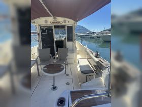 Interior view of the helm area on a fishing boat, featuring comfortable seating and a spacious layout, perfect for relaxing while out on the water.