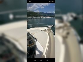 A clear view of the front deck of a yacht docked in a marina, showcasing the vessel's structure against a scenic backdrop.
