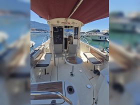 Interior view of a fishing boat's cabin featuring comfortable seating and a helm, ideal for relaxing and navigating on the water.