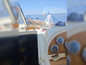 A person relaxes in the helm area of a boat, showcasing the interior space and equipment while enjoying a day on the water.