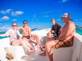 A group of friends relaxes on a boat under a bright blue sky, enjoying a sunny day on the water — perfect for social outings and adventures.