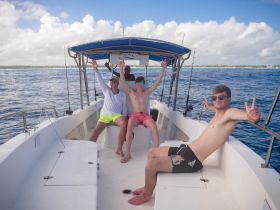 A group of friends enjoys a fun day on the boat, celebrating with smiles and peace signs — perfect for memorable adventures on the water.