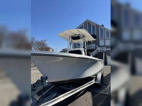 A striking view of a boat on its trailer, showcasing its sleek design against a clear blue sky and a modern house backdrop.