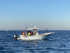 A group of anglers enjoys a day of fishing on a boat in the open ocean, showcasing the excitement of a fishing adventure.