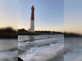 A stunning view of a lighthouse at sunset, framed by gentle waves, capturing the serene beauty of coastal scenery.