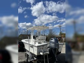 A pristine center console boat is showcased against a backdrop of blue skies and fluffy clouds, perfect for fishing or day trips on the water.
