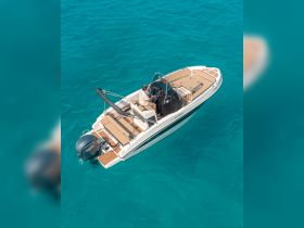 An aerial view of a boat underway with a captain at the helm, navigating through stunning turquoise waters — perfect for exploring coastal destinations.