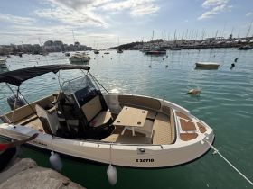 A sleek speedboat docked in a picturesque harbor, showcasing its stylish design and inviting seating area — perfect for leisurely outings on the water.
