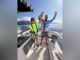 A father and son proudly display their catch while fishing on a boat, creating unforgettable memories on the open ocean.