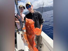 A joyful moment captured as two friends proudly display their catch while fishing in the ocean, showcasing the thrill of a successful day on the water.