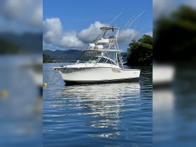 A pristine fishing boat anchored in calm waters, showcasing its sleek design and fishing gear — perfect for sport fishing adventures.