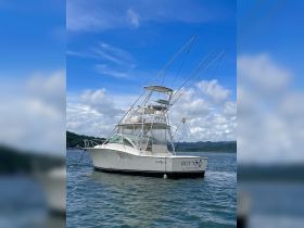 A stunning side view of the 'OUT CAST' yacht docked in calm waters, showcasing its sleek design and fishing capabilities against a picturesque backdrop.