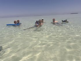 A joyful family enjoys a sandbar stop, swimming in crystal-clear waters — a perfect day for fun and relaxation under the sun.