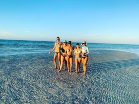 A group of friends enjoys a sunny day at the beach, celebrating together in the shallow waters — perfect for summer fun and memorable moments.