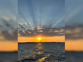 A stunning sunset casts vibrant colors over the water, creating a picturesque scene perfect for evening boat trips and relaxation on the water.