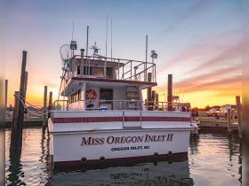 The 'Miss Oregon Inlet II' is docked at sunset, showcasing its structure against a vibrant sky — a perfect setting for fishing charters in Oregon Inlet, NC.
