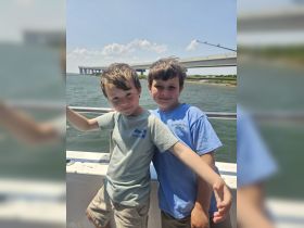 Two young boys pose happily on a boat, enjoying a sunny day on the water — a perfect moment for family adventures.