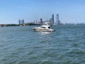 A sleek yacht cruises through the water with a stunning city skyline in the background, perfect for a day on the water.
