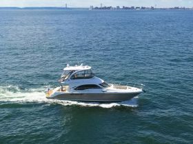 A sleek yacht cruises through the open water, showcasing its elegant design and vibrant flag — perfect for luxury outings on the sea.