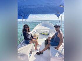 Two guests relax inside a small boat, enjoying the scenic views of the water. Perfect for intimate outings or fishing trips.