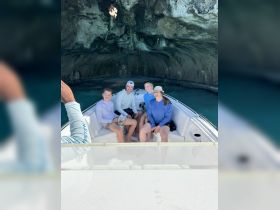 A joyful family poses for a photo inside a boat while exploring a stunning cave — a perfect adventure for creating lasting memories on the water.