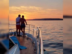 A couple embraces on the deck of a yacht, enjoying a breathtaking sunset over the water — an idyllic moment for romantic getaways or special celebrations.
