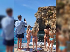 A group of friends captures the stunning coastal scenery while enjoying a day on the boat, perfect for memorable adventures and celebrations on the water.