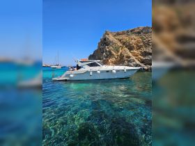 A beautiful boat anchored near a rocky coastline, with guests enjoying the clear waters — perfect for a day of relaxation and exploration.
