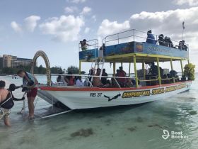 A lively group prepares for a snorkeling adventure aboard a glass bottom boat, enjoying the beautiful beach setting and clear waters.