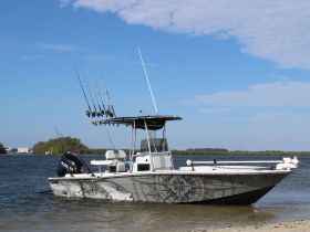 A sleek fishing boat anchored at the shore, showcasing its design and fishing gear — perfect for a day out on the water.