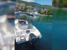 A clear view of a sleek motorboat docked in tranquil waters, showcasing its design and the surrounding scenic waterfront.