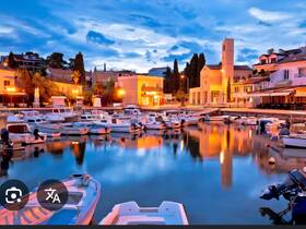 A picturesque evening scene at a harbor filled with various boats, reflecting the warm glow of nearby lights against the calm water.