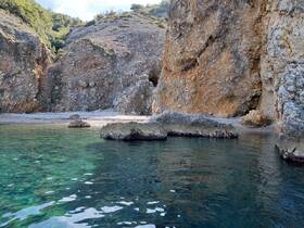 A serene view of a secluded beach surrounded by rocky cliffs and clear turquoise waters, perfect for exploring hidden gems along the coastline.