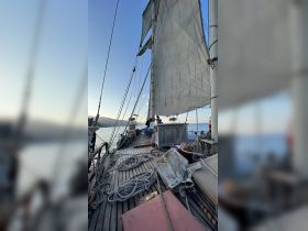 A scenic view of a sailing boat with guests enjoying the ocean breeze, perfect for sunset cruises and memorable sailing experiences.