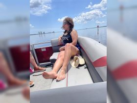 A woman relaxes on the lounge seating of a pontoon boat, enjoying a sunny day on the water — perfect for leisure and relaxation.