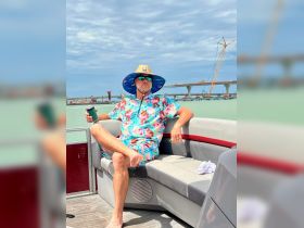 A man relaxes on a pontoon boat, enjoying a drink under the sun — a perfect scene for summer outings on the water.