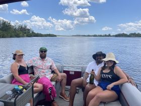 A lively group enjoys a fun day on a pontoon boat, celebrating with drinks and laughter under a sunny sky — perfect for a memorable outing on the water.
