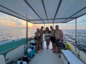 A cheerful group poses for a photo on a boat at sunset, capturing a memorable moment during their aquatic adventure.