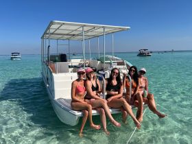 A fun group of friends relaxes on a pontoon boat in crystal-clear waters, enjoying a perfect day under the sun — ideal for beach parties and summer adventures.
