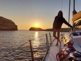 A woman enjoys a stunning sunset while sailing, capturing the essence of a perfect evening on the water.