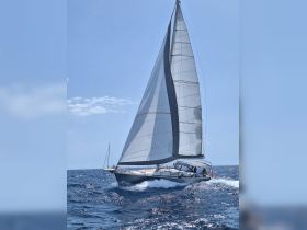 A sleek sailboat navigates through the open sea, showcasing its impressive sails and design — perfect for sailing enthusiasts and adventure seekers.